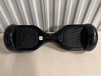 Top view of black electric hoverboard showing footpads and central pivot.