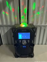 Front view of the karaoke machine showing disco ball light effects projecting green and red dots on the wall.
