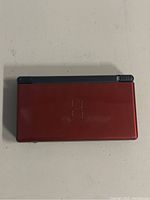 Closed red Nintendo DS Lite showing top cover with embossed logo.