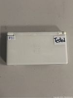 Top view closed of white Nintendo DS Lite showing logo and tested sticker