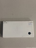 Top closed view showing white outer shell with rear camera and some dirt marks