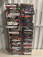 Four tall stacks of PlayStation 3 game cases arranged closely together, showing a wide variety of game titles and genres.