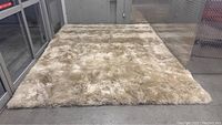 Full view of 9x12 beige lambskin rug laid flat