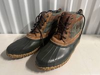 Front and angled side view of Sorel boots showing rubber lower and leather/fabric upper with laces.