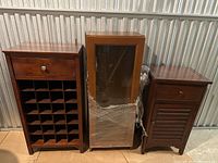 Wide shot of three vintage wooden cabinets side by side, showing the full height and design of each piece.