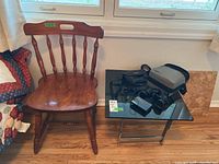 Wooden chair next to smoked glass and chrome side table holding binoculars and accessories