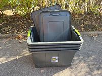 Four stacked Sterilite storage bins with lids visible, one bin's cracked corner observable.