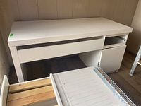 White laminated desk with drawers, one drawer detached, showing repair need