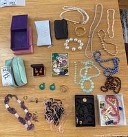Full lot layout showing assorted necklaces, earrings, boxes, and small jewelry pieces on table
