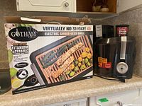 Photo of Gotham Steel electric smokeless grill box and Hamilton Beach juicer side by side on countertop.