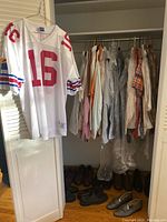 Vintage Arizona Cardinals Champion jersey hanging on door with men’s button-up shirts visible in closet and multiple shoes on floor.