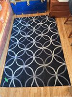 Area rug with black background and overlapping circles pattern in grey and white.
