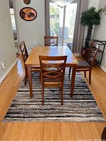 Full view of polyester rug under dining table with chairs, showing size and pattern.