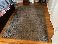 Photo of a solid brown shag rug with deep fluffy texture on hardwood floor.