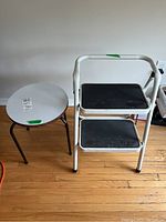 Photo showing the metal folding stepladder alongside the round plywood and metal side table on a wooden floor.