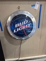 Front view of Bud Light wall clock, showing Bud Light logo, clock hands, and surround with metallic finish.