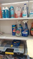 Shelf with bottles of hand soap, sanitizer, various cleaning liquids including Ajax and Foaming Bathroom Cleaner