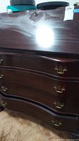 Close-up of the dark wood finish of the secretary desk showing surface scuffs and scratches, as well as brass handles on drawers.