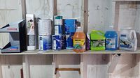 Shelf with multiple paint cans, cleaner bottles, and a Smirnoff display stand