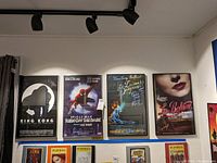 Four framed Broadway posters hung on a wall under ceiling spotlights. From left to right: King Kong, Spider-Man Turn Off the Dark, 42nd Street, and La Boheme. Each poster is roughly 22x14 inches, framed in black with glass covering.