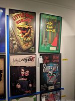 Photo showing four framed posters hung on a wall, including Little Shop of Horrors, Into the Woods, Jekyll & Hyde, and Sweeney Todd.