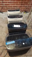Four Honeywell air purifiers arranged on carpet, black and white models visible, top control panels and front grilles shown