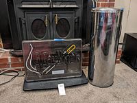 Photo of Marlboro neon advertising sign with black base and tall silver ash can beside it, placed on a carpeted floor.