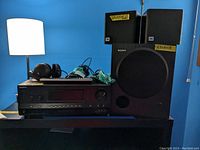 Sony stereo receiver, headphones, speakers, remote control visible on shelf against blue wall.