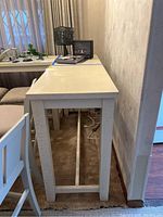 Side view of the wood-like table showing the leg design and narrow depth along a wall.