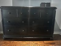 Front view of large black solid wood chest of drawers with seven drawers and round knobs