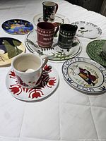 Image showing multiple Christmas-themed ceramic plates and mugs laid out on a white surface.