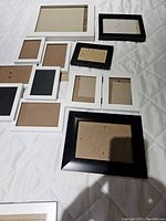 Nine monochromatic frames arranged on a white quilted surface showing various sizes and black and white finishes