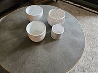 Four ceramic planters arranged on a round table, showing various textures and sizes
