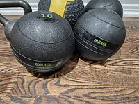 Close-up of three 10 lbs weighted balls by Rage Fitness with textured black surfaces
