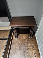 Photo of the three dark veneer nesting tables stacked together showing the turned legs and feet design.