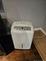 White GE dehumidifier unit showing front grille and water collection area.