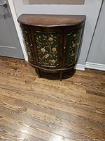 Front view of demi-lune accent cabinet on hardwood floor