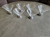 Front view showing all six martini glasses, the 4 shorter glasses in the back and 2 larger glasses in front, all with clear glass bowls and distinct metal bases.