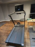 Full view of treadmill showing running deck, handrails, touchscreen and power cable