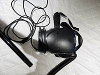 Photo of the Oreck portable vacuum laying with cord, hose, and nozzle attachment on a white surface.
