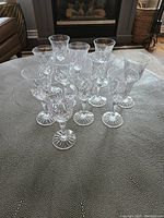 Set of 11 clear crystal white wine glasses with etched decoration and starburst pattern on base, displayed on a grey textured surface