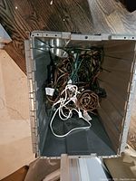 Photo of plastic storage bin containing coiled and tangled string lights with green wiring and plugs.