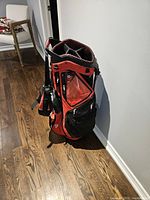 Sun Mountain stand golf bag shown standing with side pockets visible, red and black with some white accents.