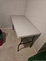 Side view of white folding utility table with metal legs