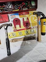 Tools including hammers, leveling tool, tape measures, wire brush, pack of Korky flappers.