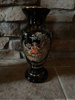 Front view of black and gold vase with detailed painted figure scene