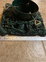 Top view of heavy cast iron Christmas tree base with three adjustable screws and ruler showing 14 inch size.
