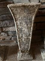 Close-up front view of tapered rectangular concrete flower pot or stand with rough surface.