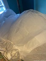 Photo showing the white crinoline petticoat spread out, illustrating the volume and layers of sheer fabric.