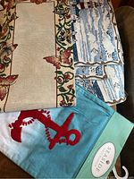 Photo of table runners and placemats showing butterfly patterned runner, lighthouse placemats with seagulls in blue and white, and tag on anchor runner.